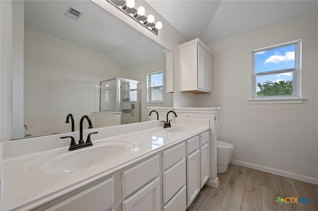 907 Pecos Cv, Leander, TX 78641 - bathroom with vaulted ceiling, wood finished floors, a stall shower, double vanity, and toilet