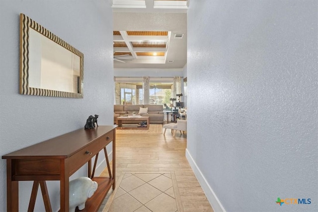 corridor with beamed ceiling, coffered ceiling, and light hardwood / wood-style flooring