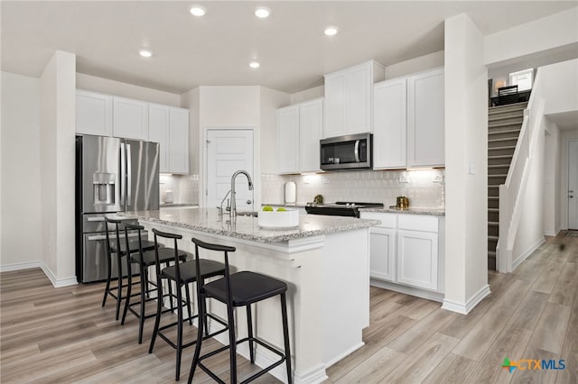 507 Dakota Crk, New Braunfels, TX 78130 - kitchen featuring appliances with stainless steel finishes, a center island with sink, light wood finished floors, a breakfast bar, and recessed lighting