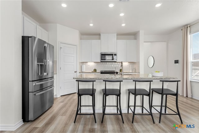 507 Dakota Crk, New Braunfels, TX 78130 - kitchen featuring appliances with stainless steel finishes, a sink, white cabinets, a center island with sink, and light wood-type flooring