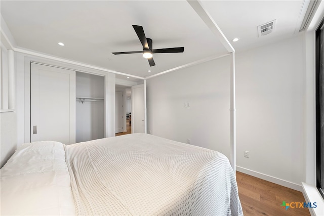 bedroom with hardwood / wood-style floors, crown molding, a closet, and ceiling fan