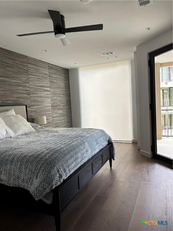 bedroom featuring access to outside, ceiling fan, hardwood / wood-style floors, and tile walls