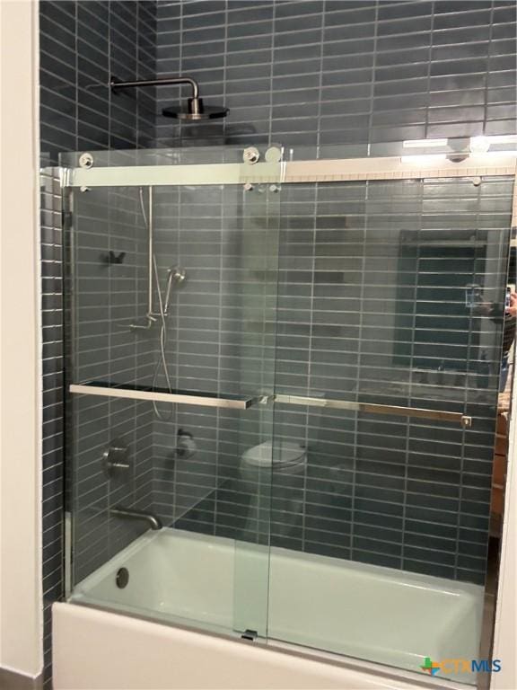 bathroom featuring bath / shower combo with glass door