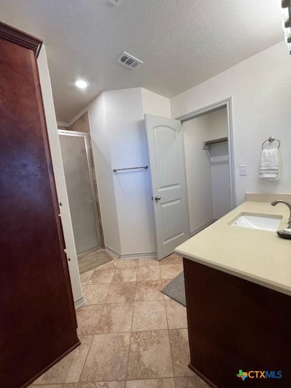 bathroom featuring visible vents, vanity, a textured ceiling, and a shower stall