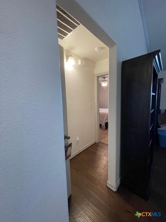 hall featuring wood finished floors, visible vents, and baseboards