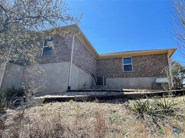 back of property with central air condition unit and brick siding