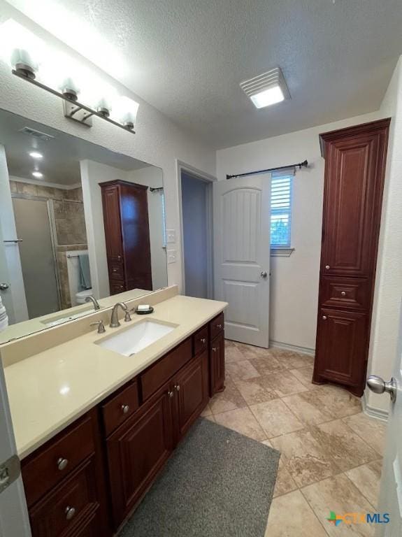 full bathroom featuring vanity, a shower stall, visible vents, and a textured ceiling