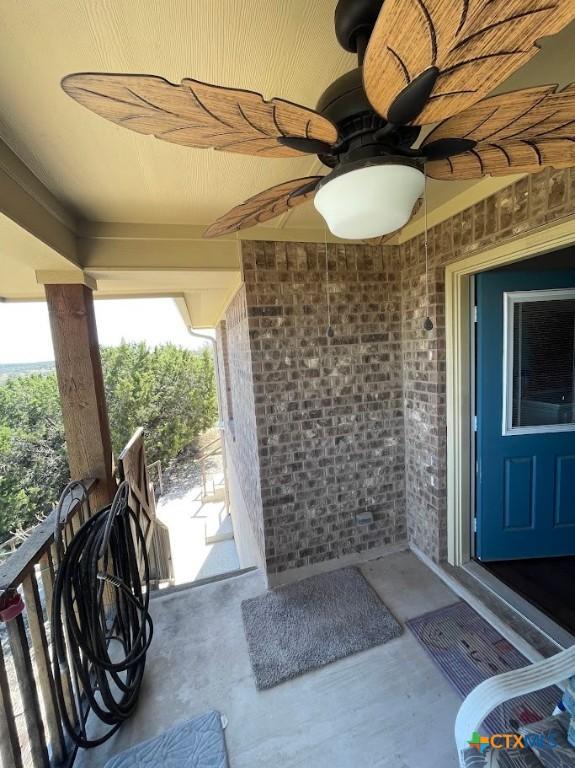 property entrance with brick siding and a ceiling fan