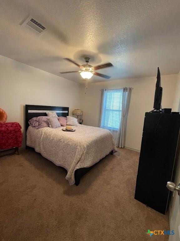 bedroom with visible vents, light carpet, a textured ceiling, and a ceiling fan