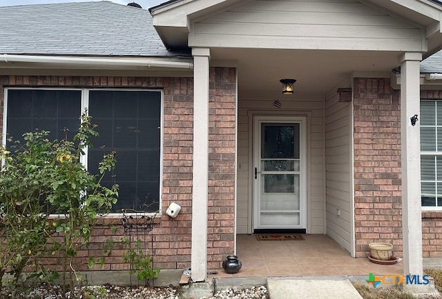 entrance to property with brick siding and roof with shingles