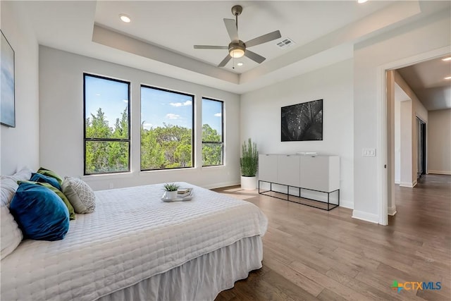 bedroom featuring a raised ceiling, ceiling fan, and wood-type flooring