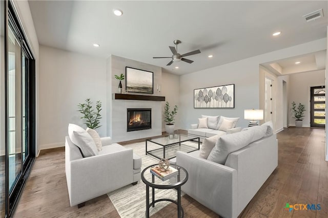 living room featuring a large fireplace, ceiling fan, and hardwood / wood-style floors