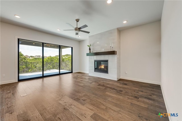 unfurnished living room featuring a tiled fireplace, ceiling fan, and dark hardwood / wood-style flooring