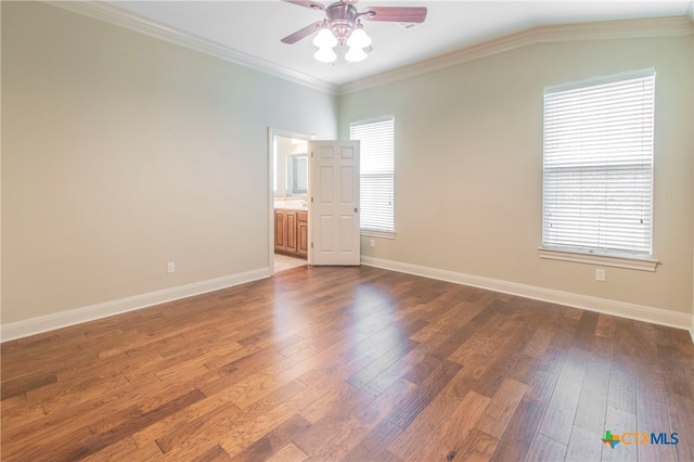 empty room with dark hardwood / wood-style flooring, ornamental molding, and a healthy amount of sunlight