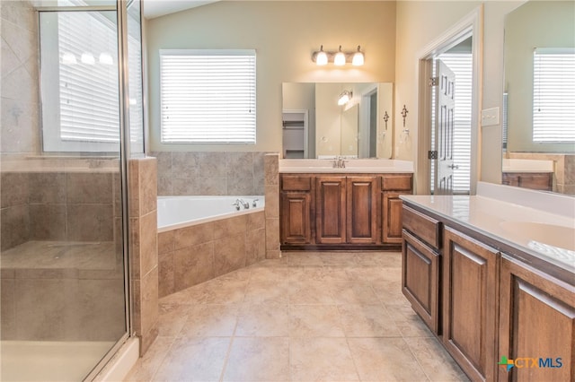 bathroom featuring tile patterned flooring, independent shower and bath, vanity, and vaulted ceiling