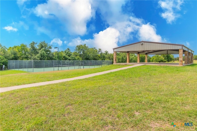 view of community with tennis court and a lawn