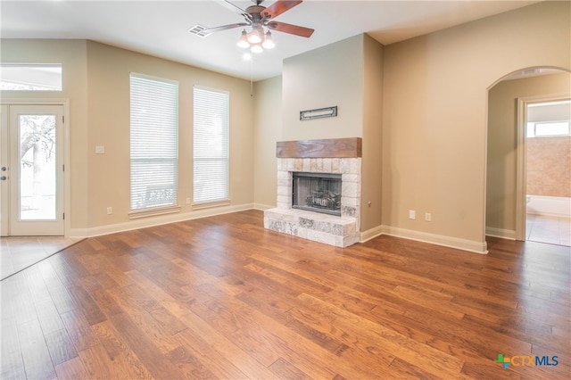 unfurnished living room with wood-type flooring, ceiling fan, and a fireplace