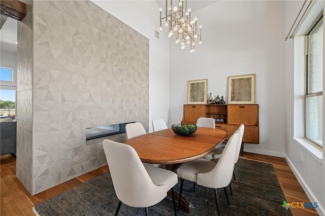 215 Mesa Vista Dr, Leander, TX 78641 - dining room featuring an accent wall, tile walls, wood finished floors, a high ceiling, and a chandelier