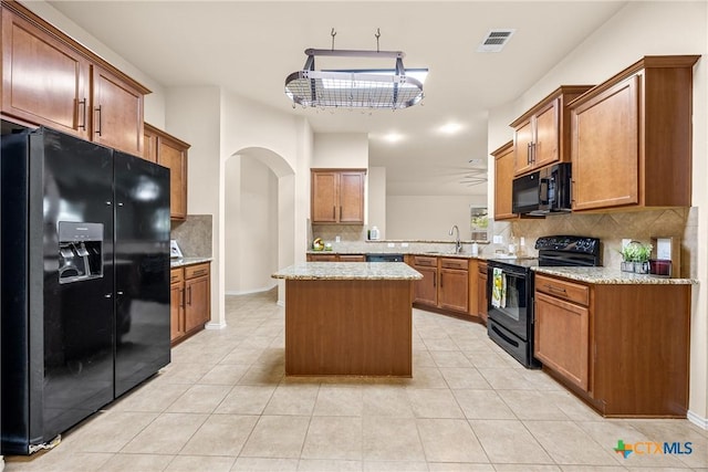 5507 Sulfur Spring Dr, Killeen, TX 76542 - kitchen featuring black appliances, arched walkways, decorative backsplash, a kitchen island, and brown cabinets