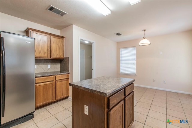 kitchen featuring stainless steel refrigerator, decorative backsplash, hanging light fixtures, a center island, and light tile patterned floors