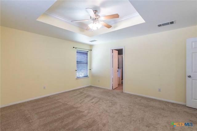 carpeted spare room with crown molding, a raised ceiling, and ceiling fan