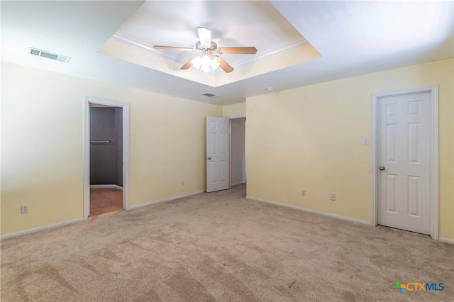 unfurnished bedroom featuring crown molding, light carpet, and a tray ceiling