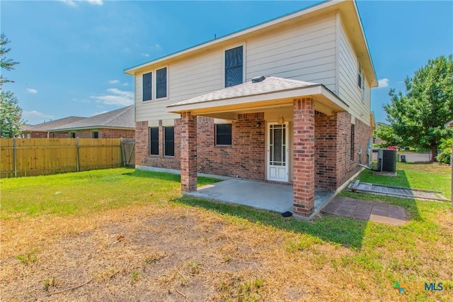 back of property with central air condition unit, a patio area, and a lawn