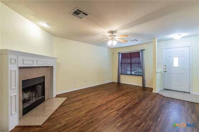 unfurnished living room with hardwood / wood-style flooring, a tile fireplace, and ceiling fan