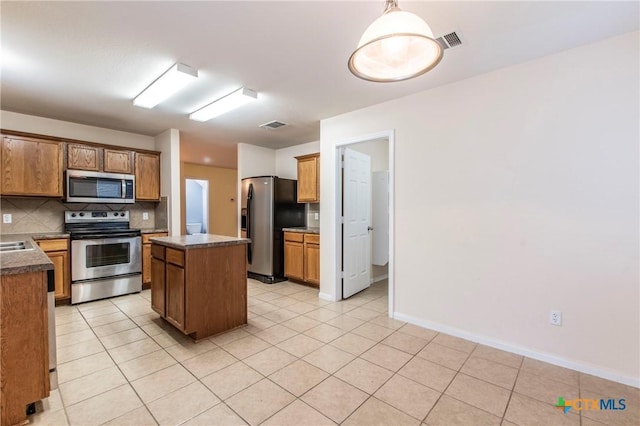 kitchen featuring decorative light fixtures, backsplash, a center island, light tile patterned floors, and stainless steel appliances