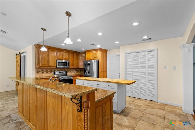 305 Berwick St, Victoria, TX 77904 - kitchen featuring stainless steel appliances, a peninsula, tasteful backsplash, a barn door, and light stone countertops