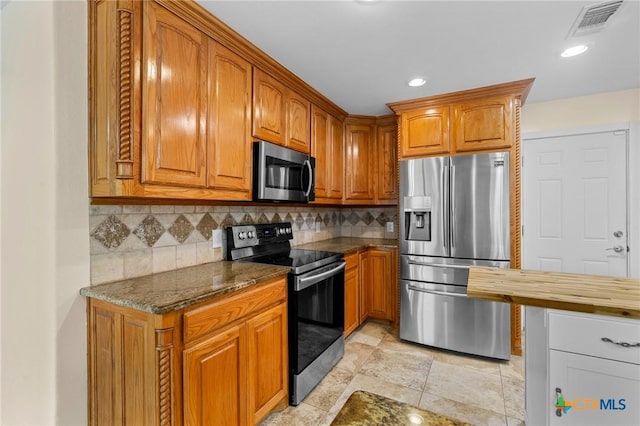 305 Berwick St, Victoria, TX 77904 - kitchen featuring stainless steel appliances, brown cabinetry, decorative backsplash, dark stone countertops, and recessed lighting