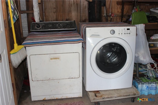 laundry room with wood walls and washer and dryer