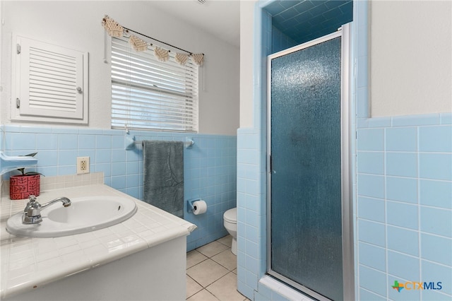 812 Merritt Dr, Lockhart, TX 78644 - bathroom featuring tile walls, tile patterned flooring, a stall shower, vanity, and wainscoting