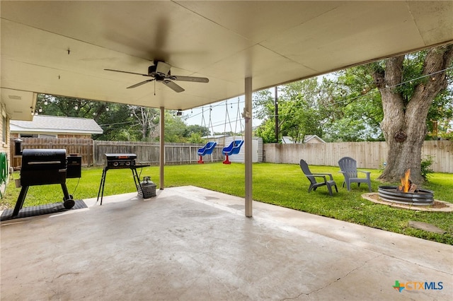 812 Merritt Dr, Lockhart, TX 78644 - fenced backyard with a playground, a fire pit, a patio area, and a ceiling fan