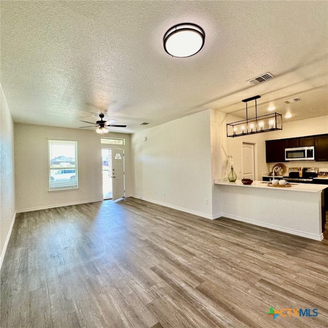 unfurnished living room with dark wood-type flooring, a textured ceiling, and ceiling fan