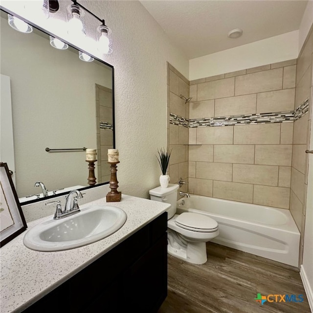 full bathroom featuring toilet, tiled shower / bath combo, vanity, and hardwood / wood-style floors