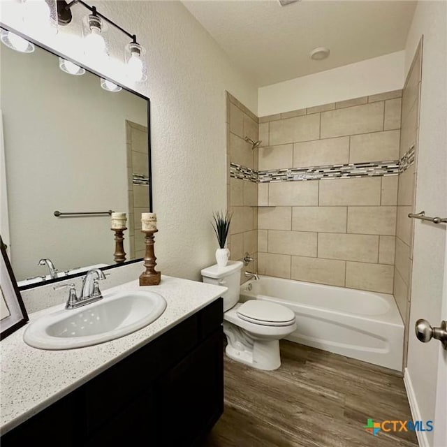 full bathroom featuring toilet, tiled shower / bath combo, vanity, and hardwood / wood-style floors