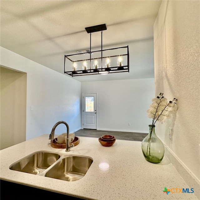 kitchen featuring sink, hanging light fixtures, and light stone countertops