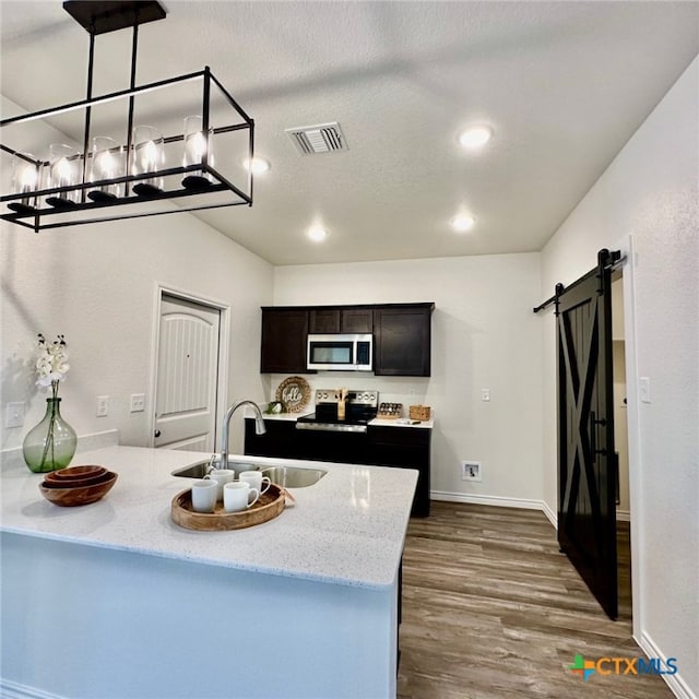 kitchen with stainless steel appliances, sink, decorative light fixtures, kitchen peninsula, and a barn door