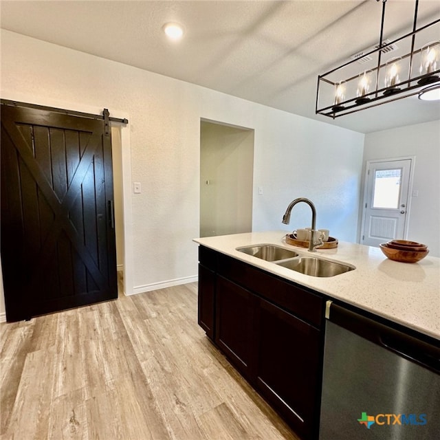 kitchen with dishwasher, a barn door, hanging light fixtures, light wood-type flooring, and sink