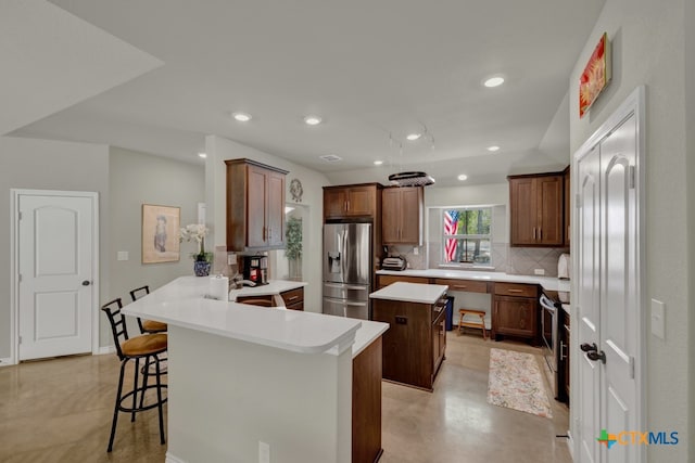 kitchen with a kitchen bar, stainless steel appliances, a kitchen island, decorative backsplash, and kitchen peninsula