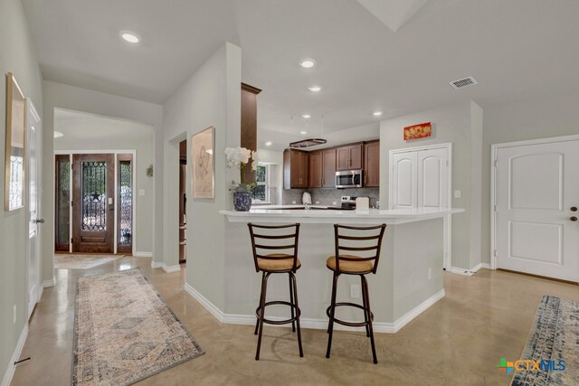 kitchen with tasteful backsplash, plenty of natural light, kitchen peninsula, and appliances with stainless steel finishes