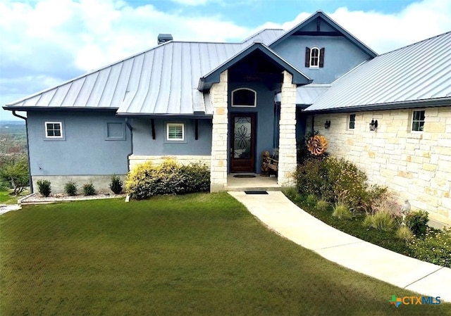 view of front of house featuring a front lawn, stucco siding, metal roof, stone siding, and a standing seam roof