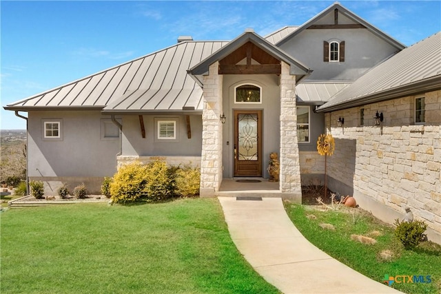 view of exterior entry featuring a standing seam roof, stucco siding, stone siding, a lawn, and metal roof