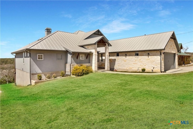 view of front of house with a front yard, a standing seam roof, a chimney, stone siding, and metal roof