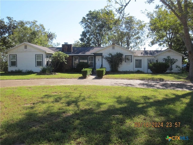 1124 Refugio Hwy, Victoria, TX 77905 - ranch-style home featuring a front lawn, board and batten siding, a chimney, and curved driveway