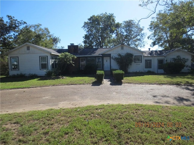 1124 Refugio Hwy, Victoria, TX 77905 - ranch-style house featuring a front yard, a chimney, and board and batten siding