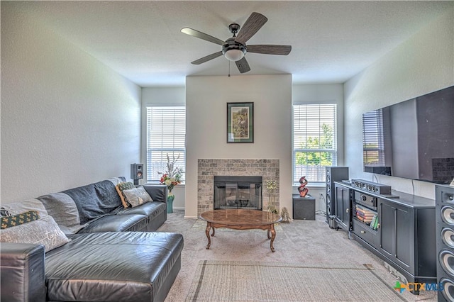 living area featuring light carpet, a wealth of natural light, a ceiling fan, and a glass covered fireplace