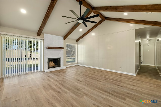 unfurnished living room featuring ceiling fan, a fireplace, light hardwood / wood-style floors, and lofted ceiling with beams