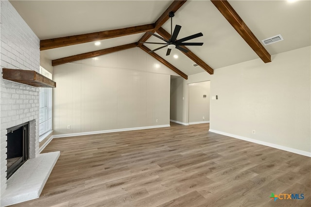 unfurnished living room featuring a brick fireplace, lofted ceiling with beams, hardwood / wood-style floors, and ceiling fan